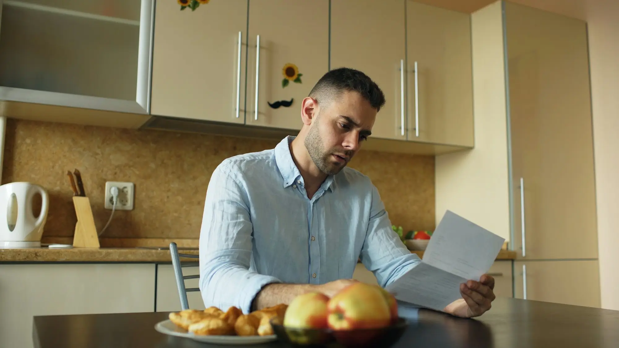 Business owner reading an official letter at his kitchen table before working out how to clear a tax debt
