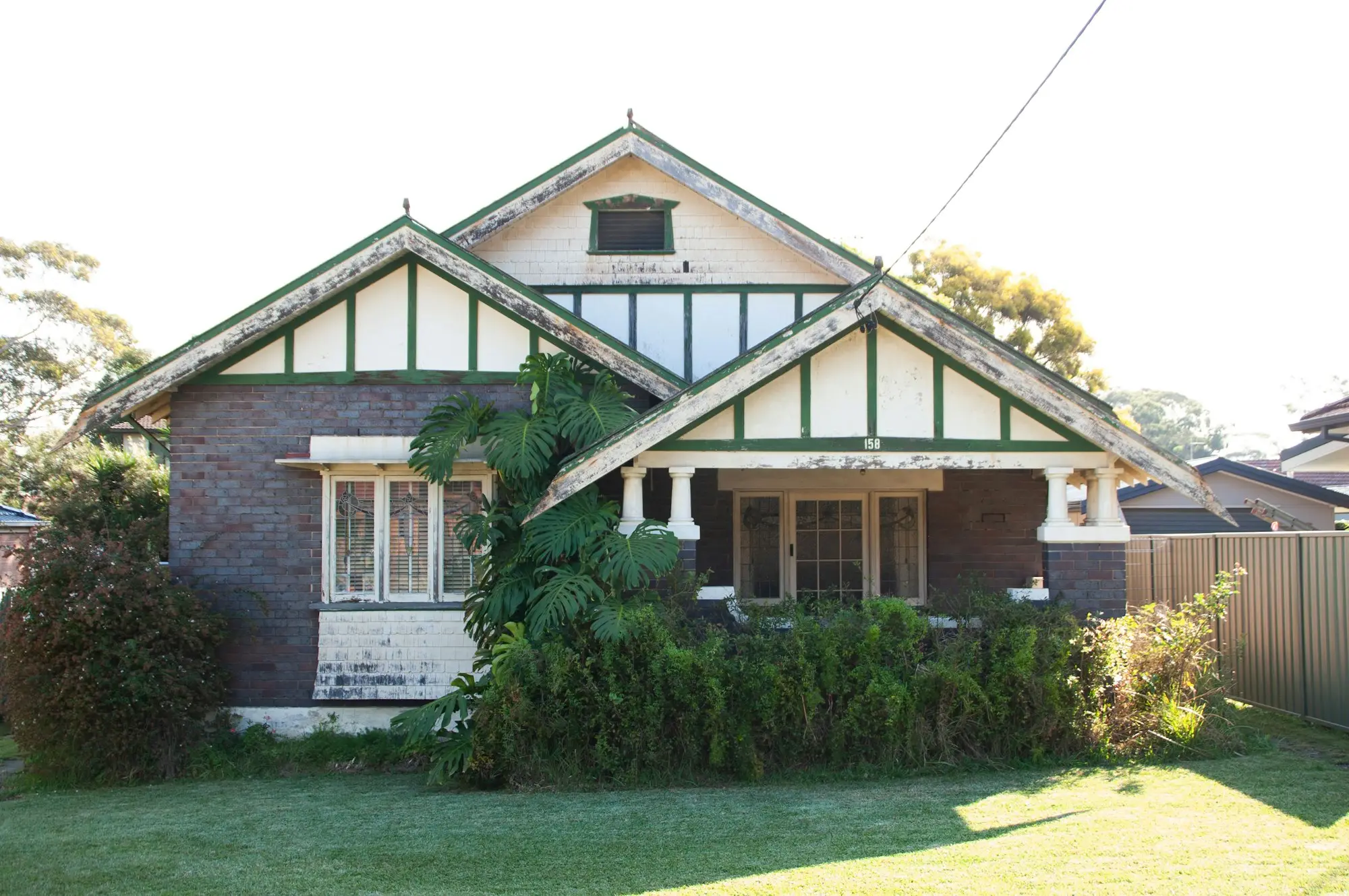 Federation-style brick bungalow with twin gables and a garden fence on a Sydney street