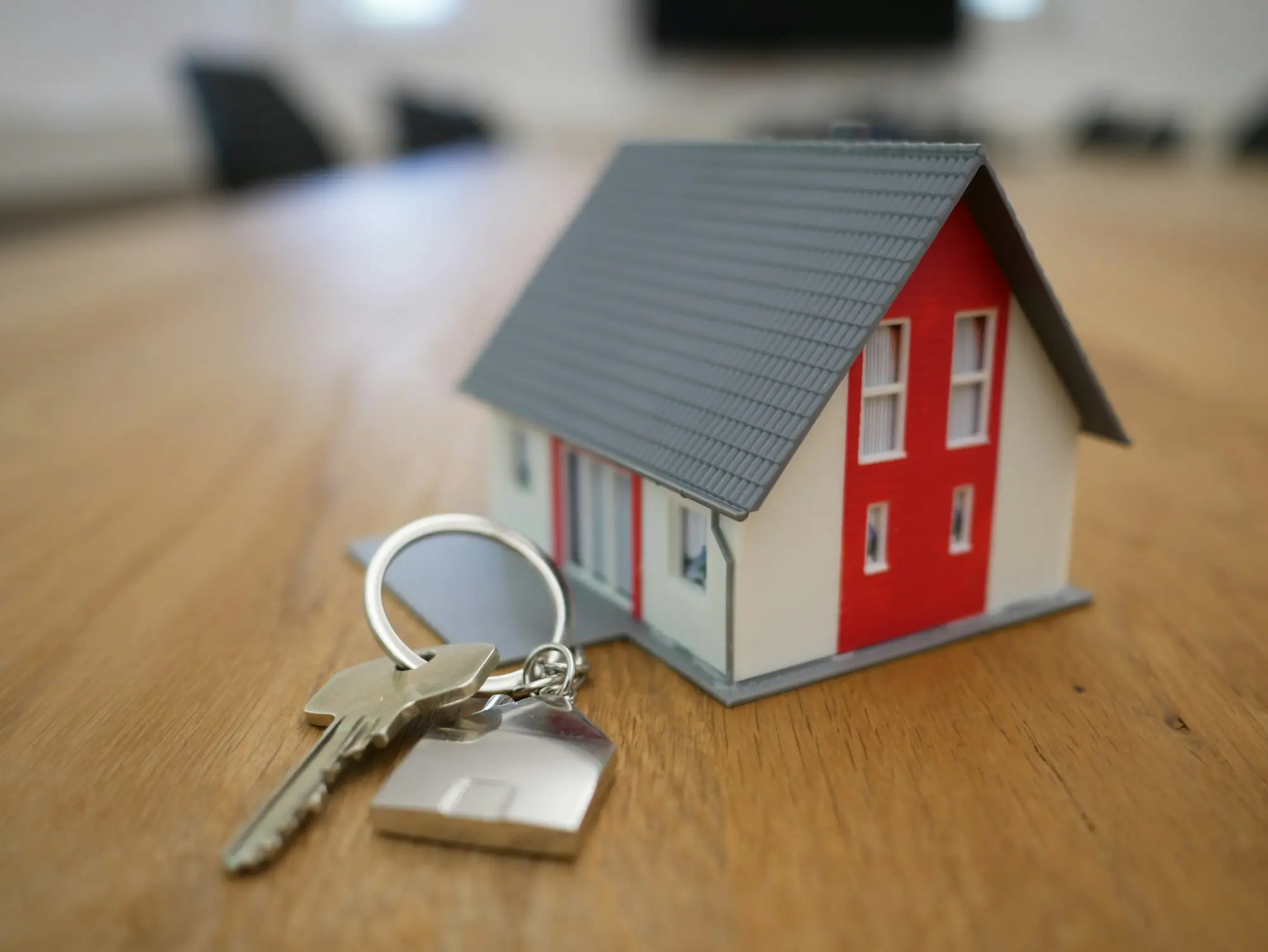 House keys beside a small model house on a desk, ready for a property-secured loan settlement