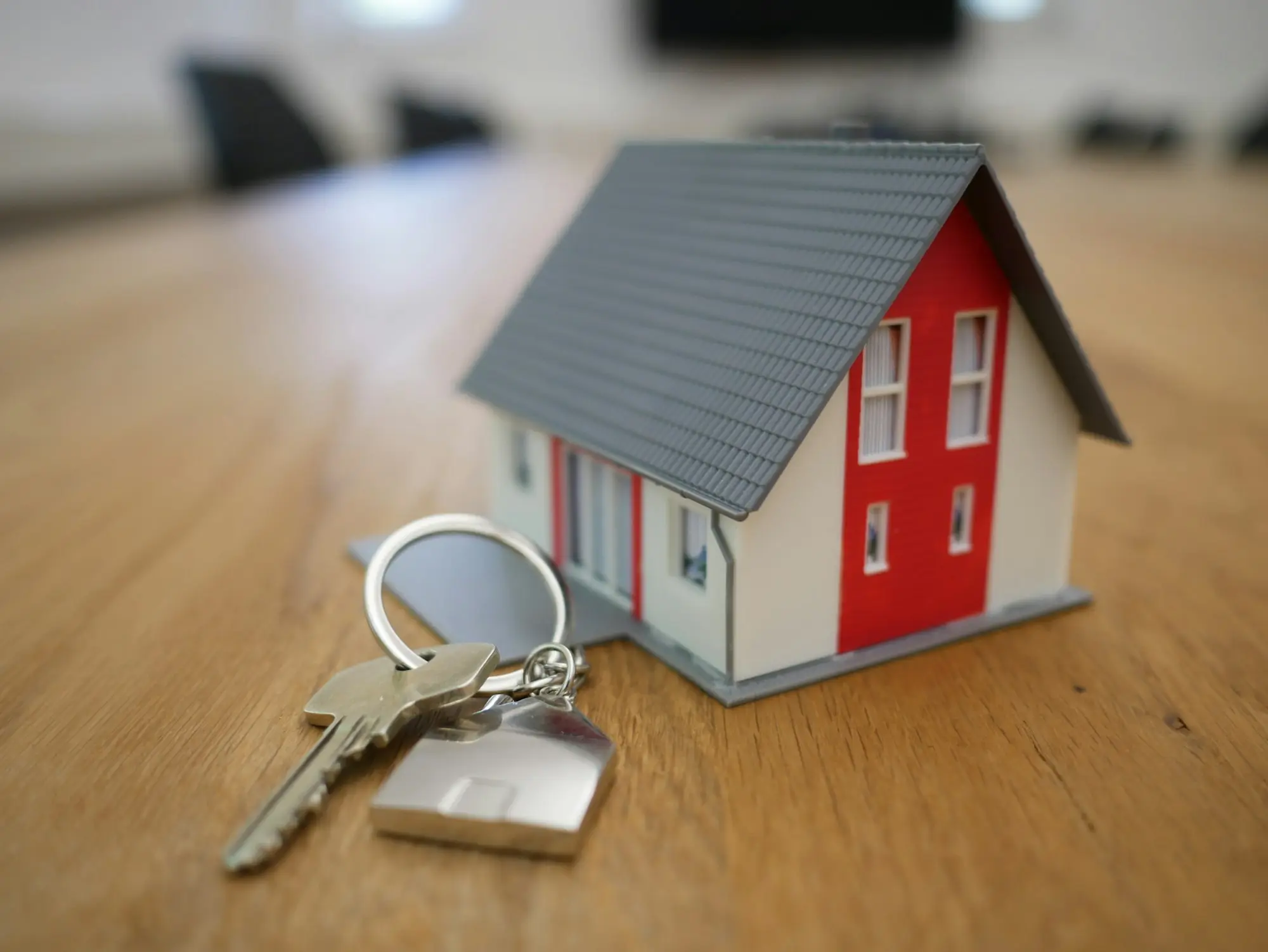 House keys beside a small model house on a desk, ready for a property-secured loan settlement