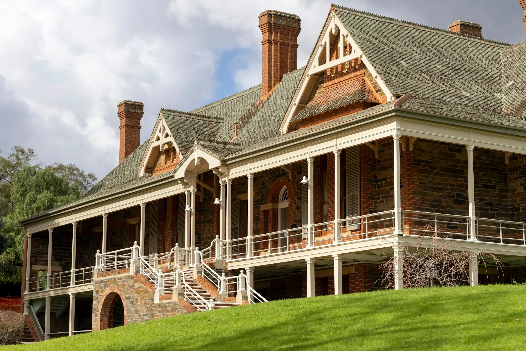 Grand verandah home with brick chimneys and timber fretwork set on a green lawn