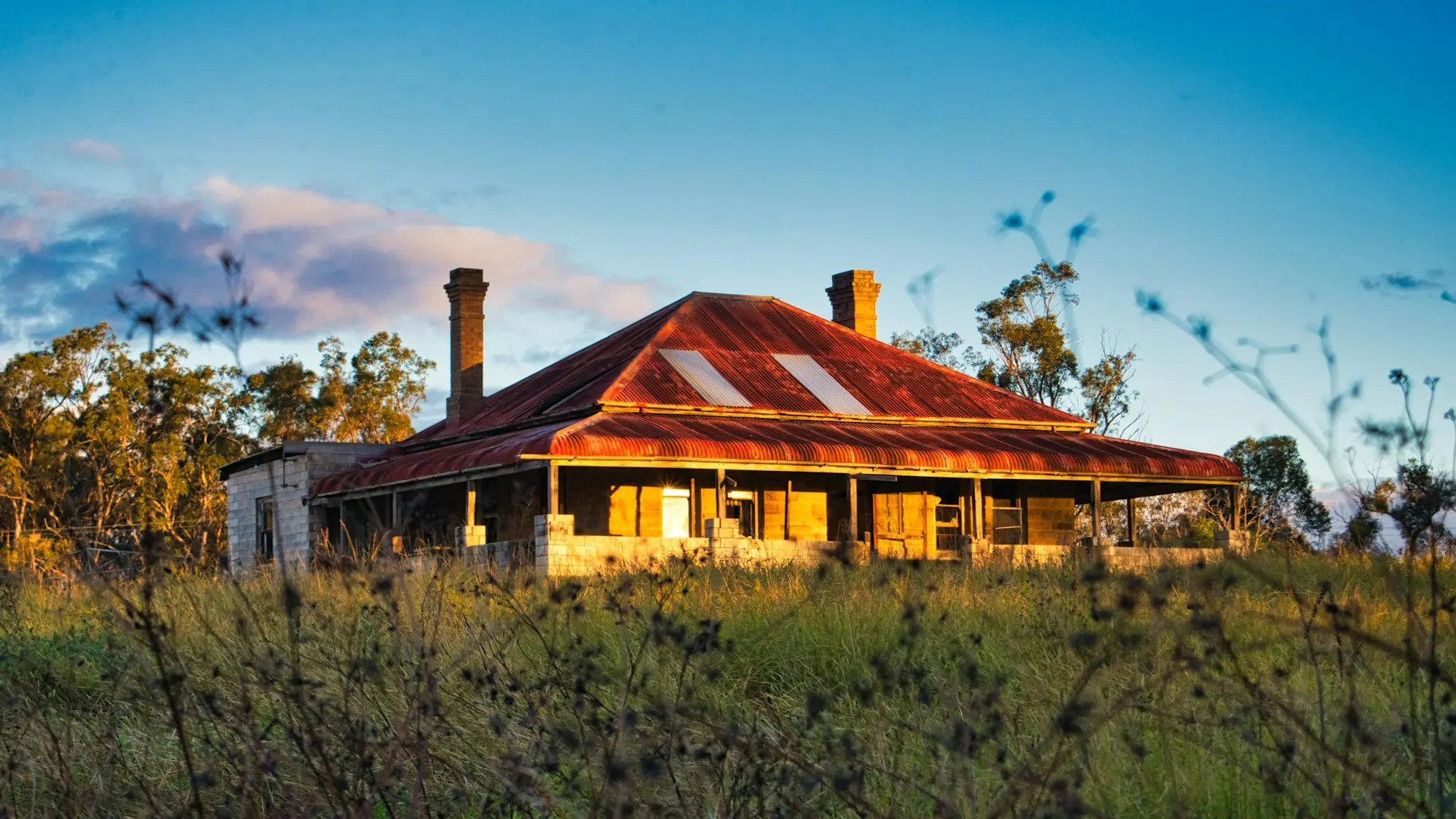 Old country homestead with a red iron roof catching the late afternoon sun in rural Australia