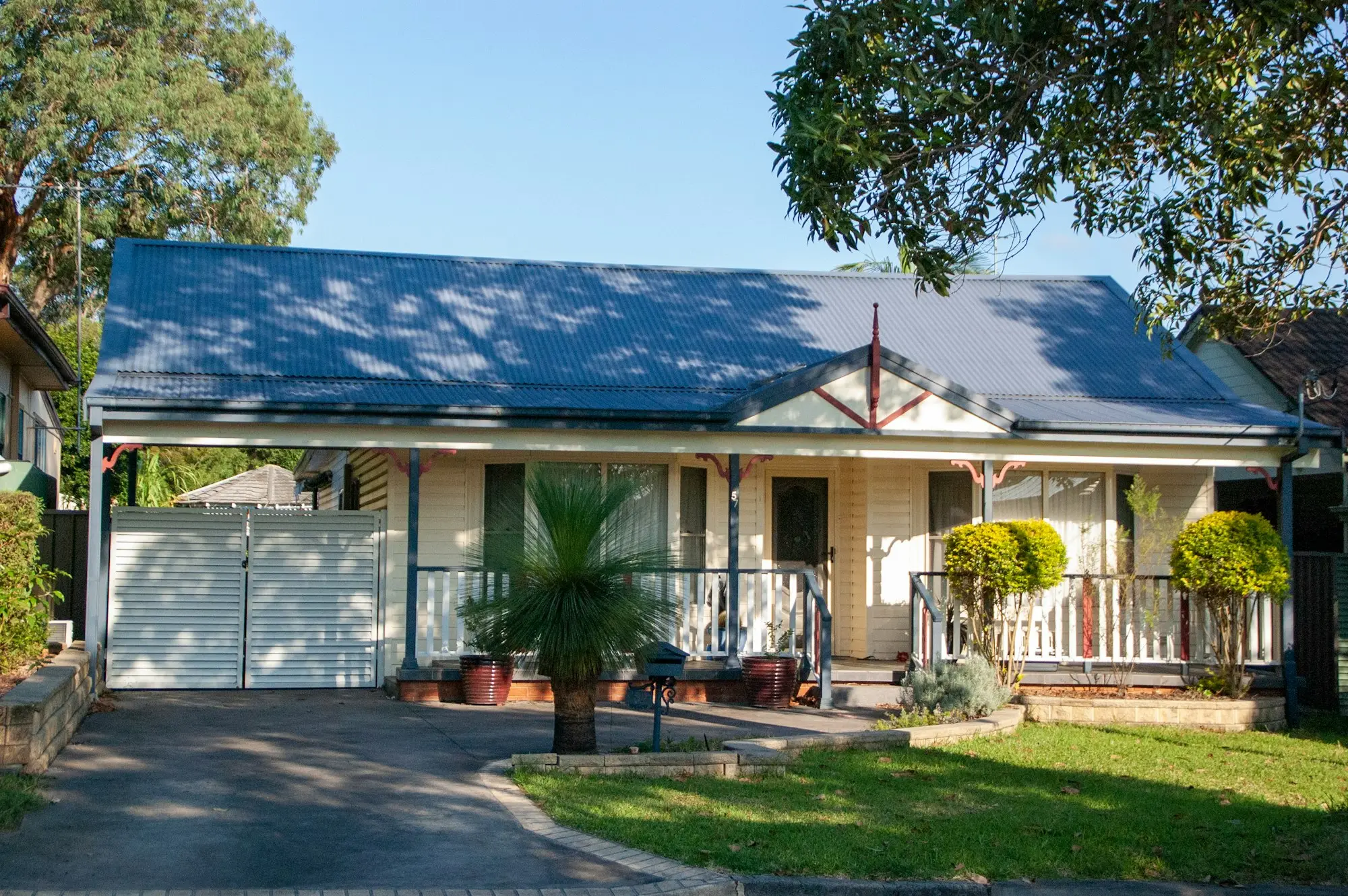 Suburban Australian home with a blue iron roof, front verandah and a tidy front garden
