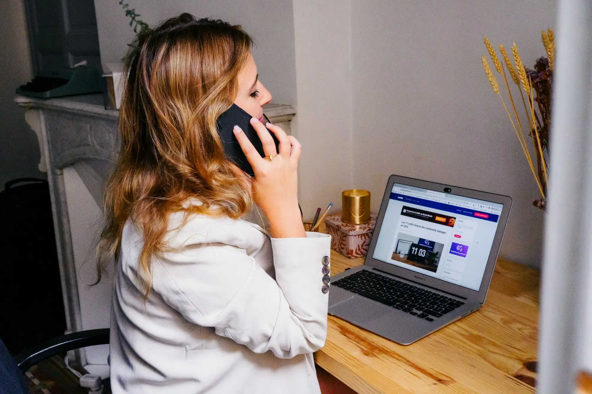 Business owner on the phone at her desk with a laptop open, working to a funding deadline