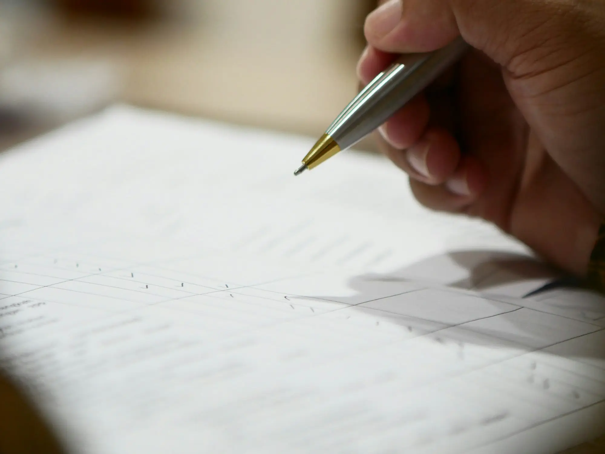 Business owner's hand holding a pen over the fine print of a supplier credit application, the kind of form that can contain a charging clause