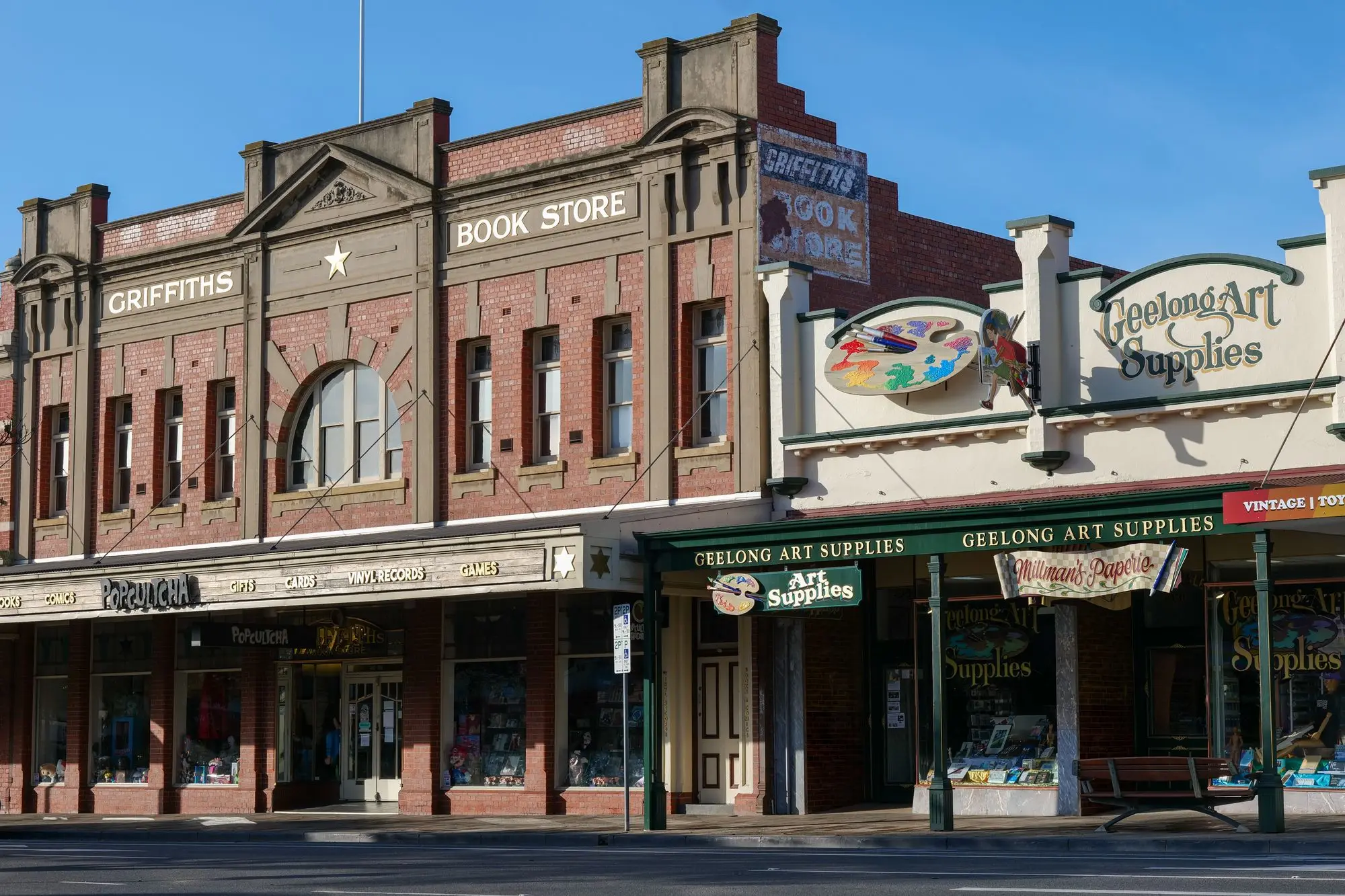 Row of heritage brick shopfronts housing a bookstore and an art supplies shop on a sunny Geelong street in Victoria